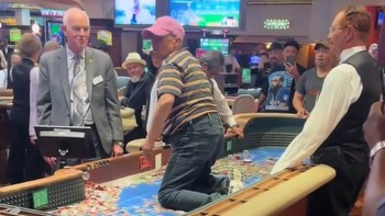 Woman climbs onto craps table at Silver Legacy Casino in Las Vegas and flings chips into the air